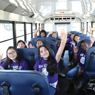 A group of kids wearing purple shirts in a school bus
